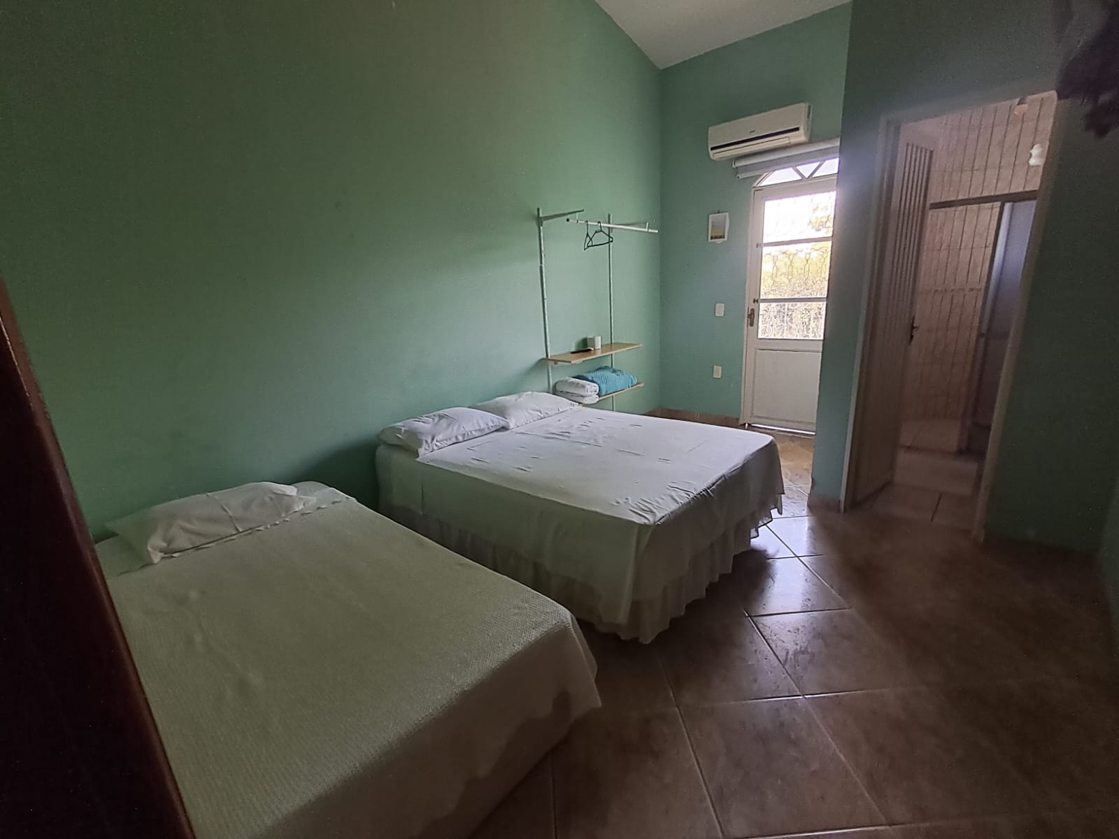 Quarto verde com cama de casal e cama de solteiro